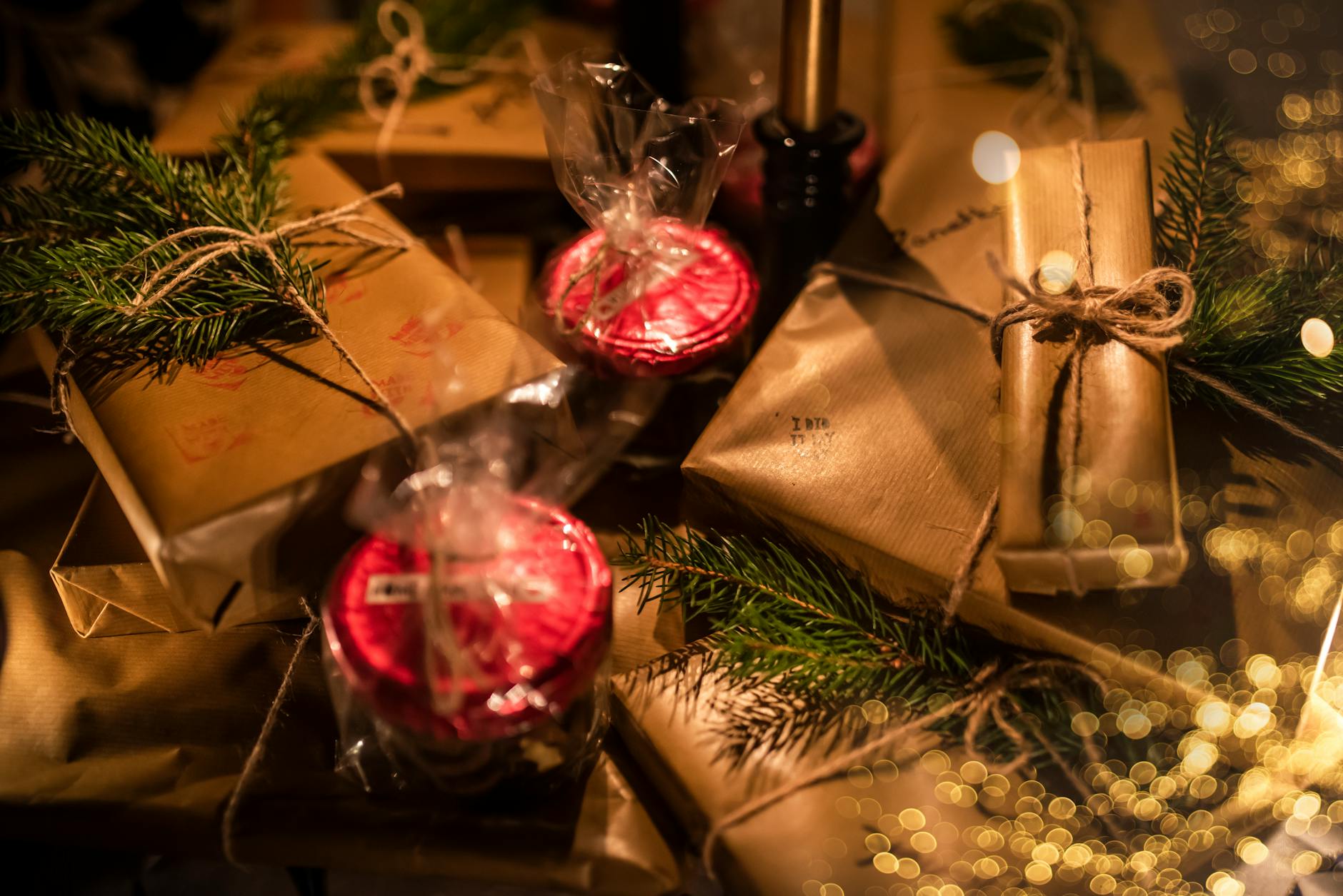 Various present boxes in wrapping paper with decorative candles and coniferous tree sprigs during New Year holiday